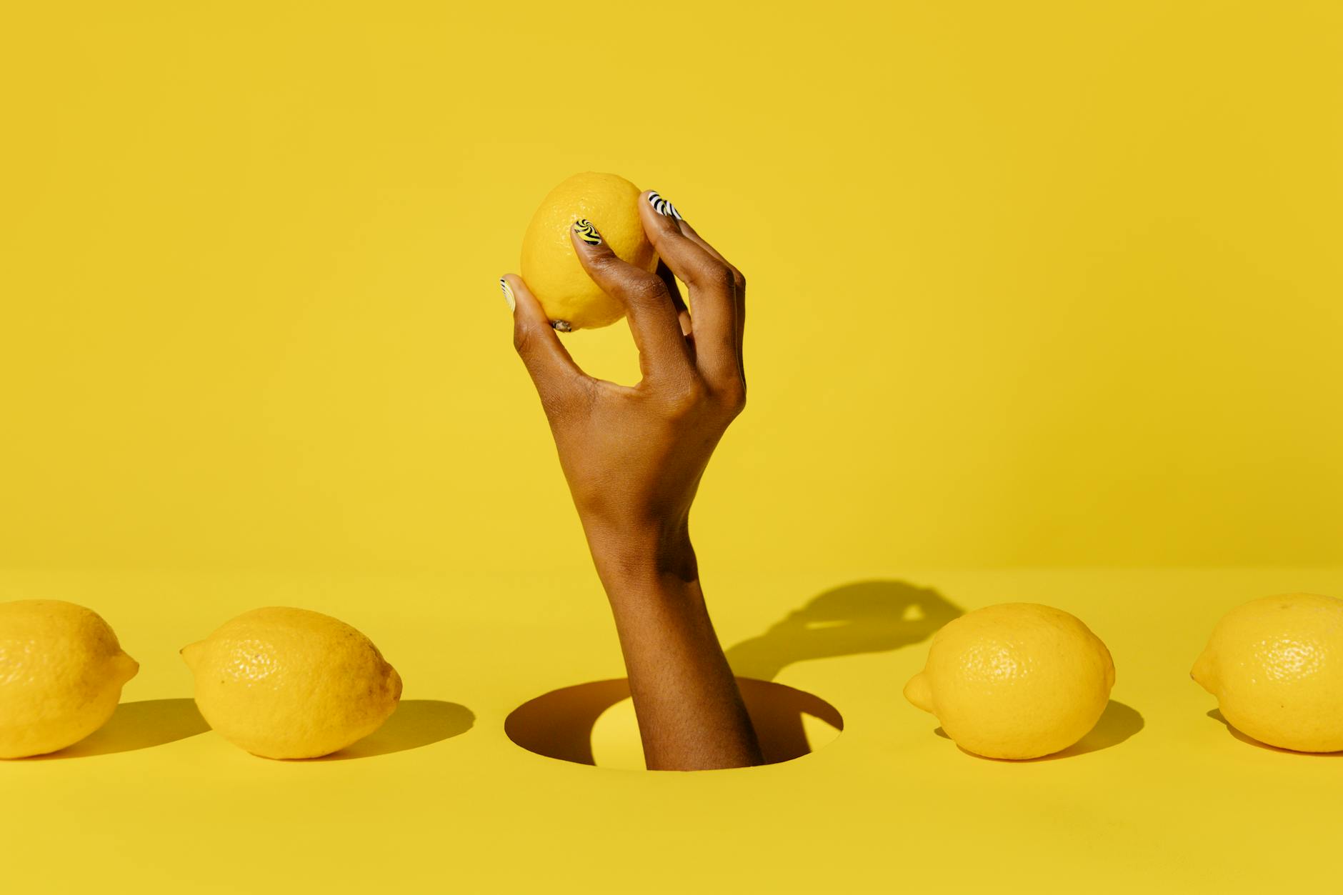 Hands holding pink and blue silicone vibrators against a pastel background