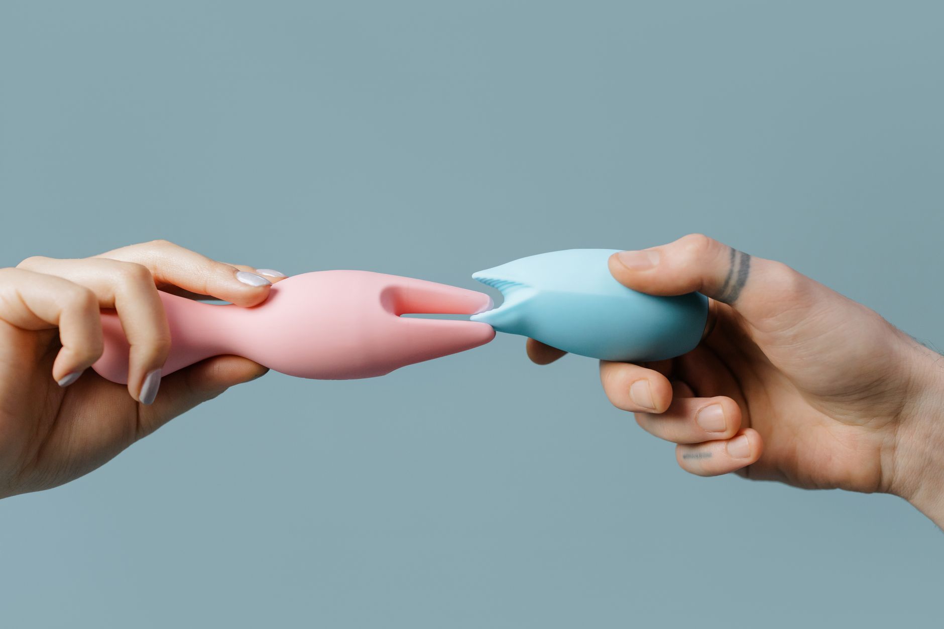 Two hands holding colorful silicone vibrators, representing choices and partnership in intimacy