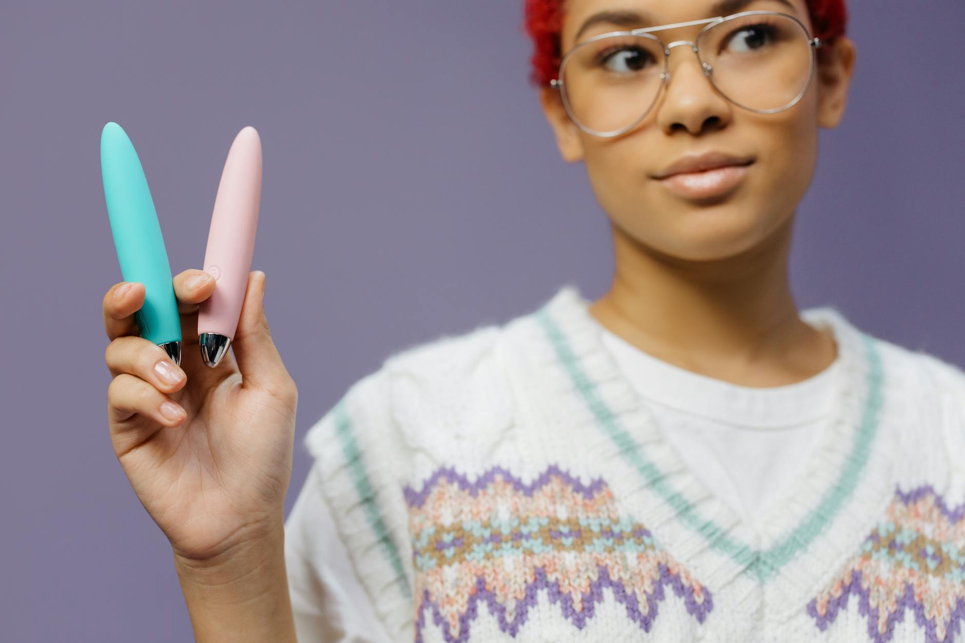 Woman holding two colorful vibrators against a purple background