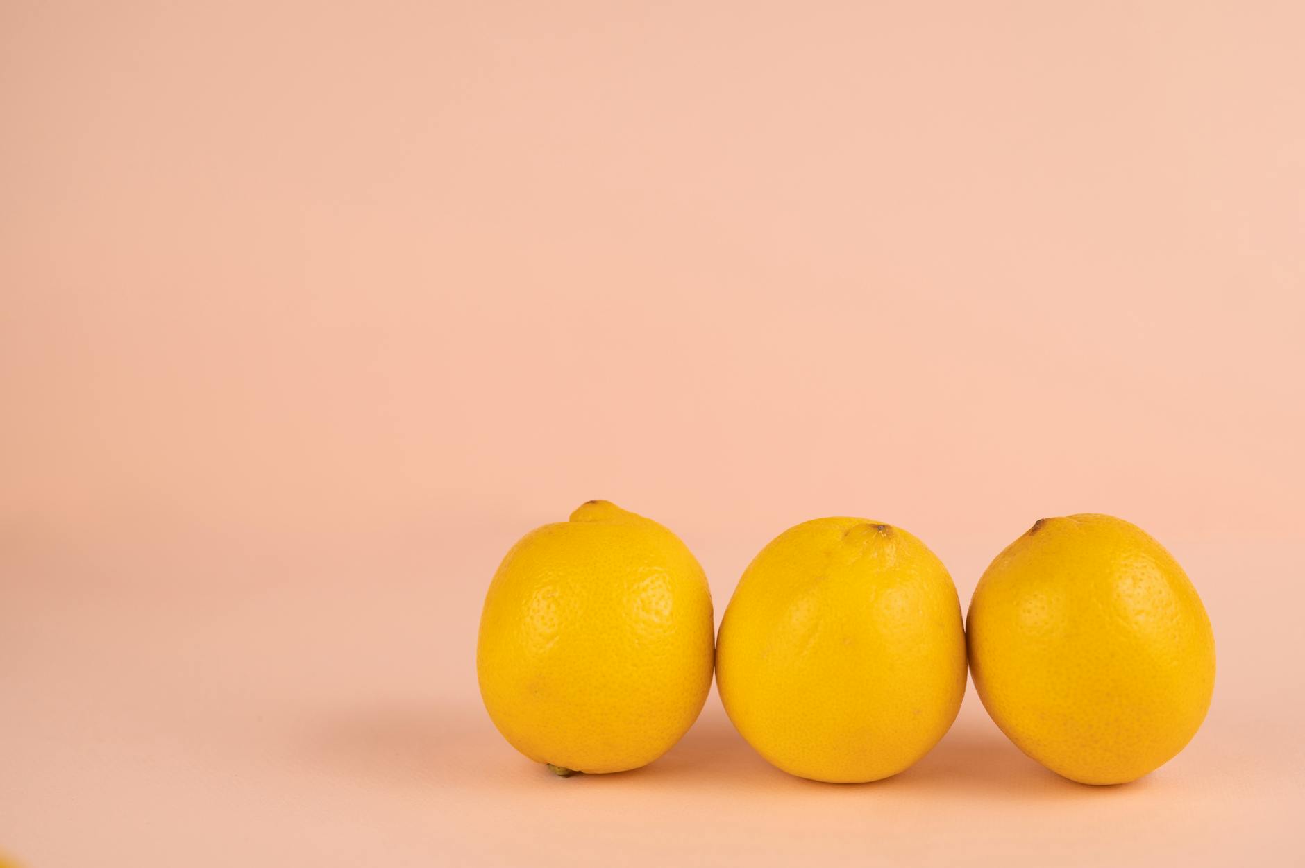 Bright yellow lemons arranged on a pastel green background, creating a fresh and vibrant flat lay composition